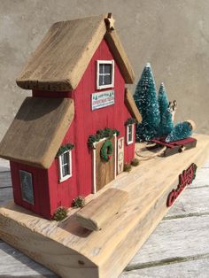 a small red house sitting on top of a wooden table next to a christmas tree