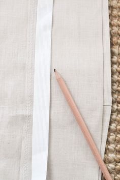 a pencil laying on top of a piece of cloth next to a crochet hook