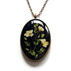 a necklace with flowers painted on it is hanging from a ball chain that has an oval pendant attached to it