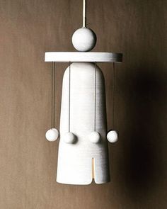 a white sculpture with three balls hanging from it's head and two strings attached to it