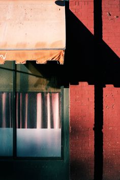 the shadow of an umbrella is cast on a brick building's wall and window