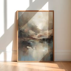 an abstract painting in a wooden frame on the floor next to a wall with white walls