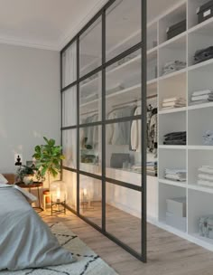 a bedroom with white walls and shelves filled with clothes, candles and other items on the floor