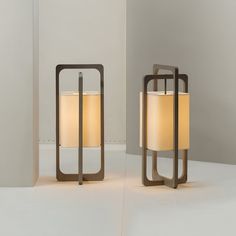 two lamps sitting next to each other on top of a white floor in front of a wall