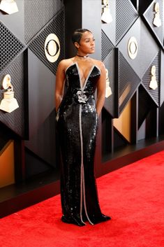 a woman standing on top of a red carpet wearing a black and white dress with silver accents