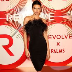 a woman in a black dress standing on a red and white carpet with the words revolve x palms