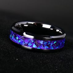 a ring with blue and purple stones inlayed to the side on a black surface