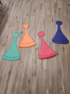 four pieces of colored plastic sitting on top of a wooden floor next to each other