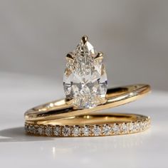 two yellow gold wedding rings with a pear shaped diamond in the center and side stones on each band