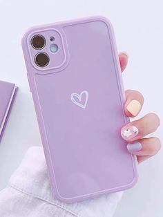 a woman's hand holding an iphone case with a heart sticker on it