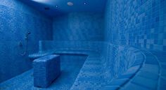 a blue tiled room with a bench in the middle and tile walls on both sides