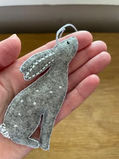 a hand holding a gray felt dog ornament