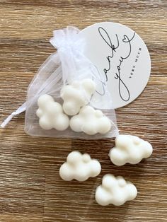 small white clouds are in a clear bag on a wooden table with a name tag