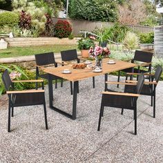 an outdoor dining table with six chairs and plates of food on it in the middle of a garden