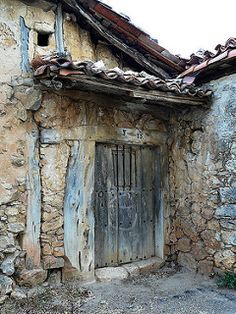 an old stone building with a wooden door and tiled roof, in the country side