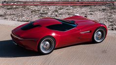 a red sports car is parked on the side of the road in front of some rocks