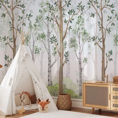 a child's room with a teepee tent and trees on the wall