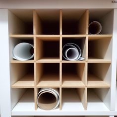 the shelves are made out of cardboard and have white cups in them on each shelf