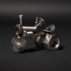 a metal object that is sitting on a black surface with screws and nuts attached to it