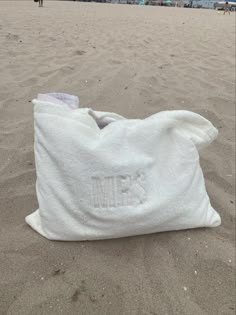 a white bag sitting on top of a sandy beach