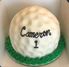 a birthday cake with a golf ball and name written on the top, in a box