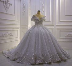 a wedding dress is displayed on a mannequin in front of a white wall