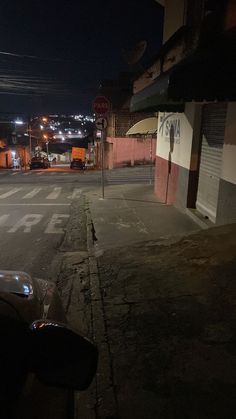 an empty street at night with cars parked on the side and no one in sight