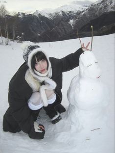 a woman kneeling down next to a snowman