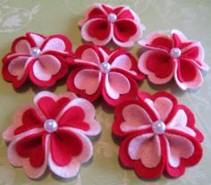 a group of red and white flowers sitting on top of a table next to each other