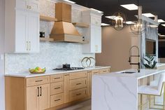 a kitchen with white cabinets and marble counter tops, gold accents on the hood over the stove