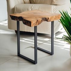 a wooden table sitting on top of a white floor next to a potted plant