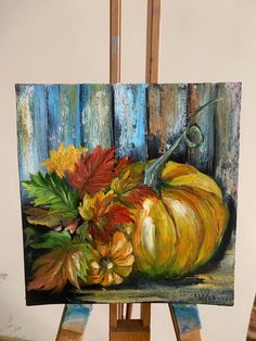 an easel with a painting of a pumpkin and flowers on it, painted in acrylic paint