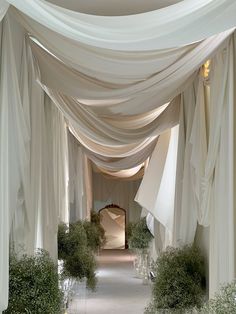 an archway is decorated with white drapes and greenery