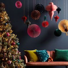 a christmas tree with ornaments hanging from it's sides and a couch in the foreground