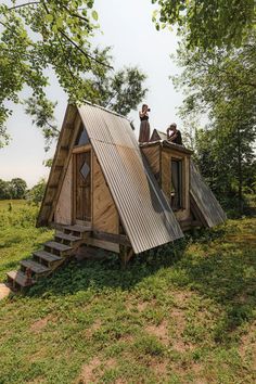 two people sitting on the roof of a tiny cabin