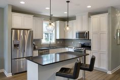 a kitchen with an island and two chairs in front of the counter top, along with white cabinets