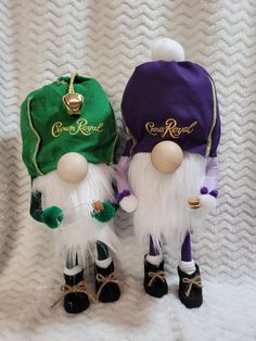 two small gnomes wearing green and purple hats on white blanketed surface with gold lettering