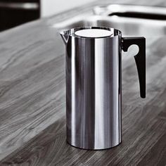 a stainless steel coffee pot sitting on top of a wooden counter