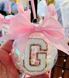 a hand holding a glass ornament with the letter g on it