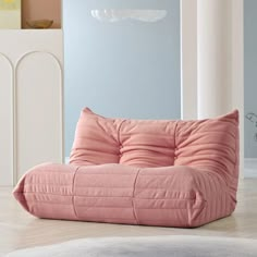 a pink bean bag chair sitting on top of a wooden floor next to a white wall