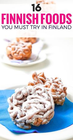 two white plates topped with cookies covered in powdered sugar on top of blue napkins