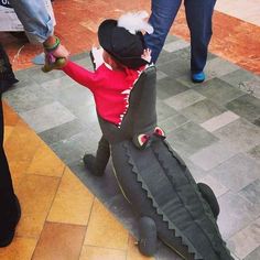 a small child in a costume is playing with an alligator