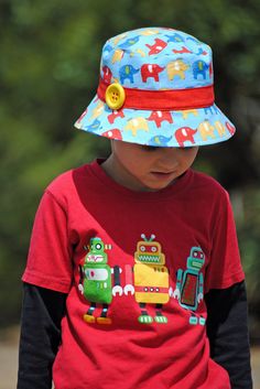 a young boy wearing a blue hat with elephants on it and a red t - shirt