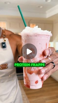 a woman holding up a pink drink in her hand with the words protein frappe on it