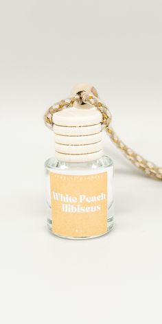 a bottle of white peach blossom perfume with a gold chain around it's neck