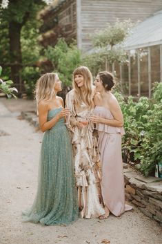 three women standing next to each other in dresses