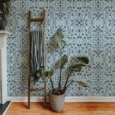 a potted plant in front of a blue wallpaper with an ornate pattern on it