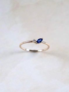 Flower inspired petal ring. Whimsical and dainty. The ring is accompanied by a beautiful blue sapphire in marquise cut and a round brilliant diamond. Blue sapphire represents wisdom, everlasting love and it is a September birthstone. 1 x Blue sapphire in marquise cut. Measures 6x3 mm. 1 x Round brilliant diamond sizes 1.5 mm. VS quality. 1.3 mm ring band. Made of 10K solid gold. Tiny Marquise Ring, Dainty Sapphire Ring, Blue Sapphire Marquise Ring, Vintage Blue Sapphire Ring, Tiny Diamond Necklace, Petal Ring, Graduation Ring, Marquise Sapphire, Graduation Rings