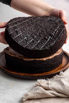 a person holding two chocolate cakes on top of each other