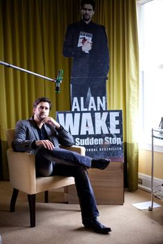 a man sitting in a chair next to a poster